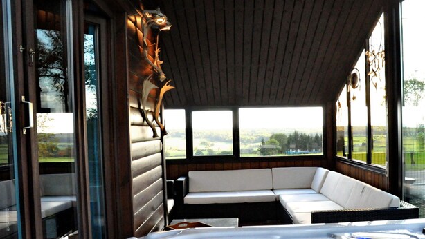A hot tub with a wooden bench and a view of the outdoors. - Chalet in Durbuy With Jacuzzi & Garden (Somme-Leuze)
