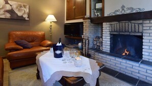 A cozy living room with a fireplace, leather sofa, and a table set for a small gathering. - Cozy Family Holiday Home (La Roche-en-Ardenne)