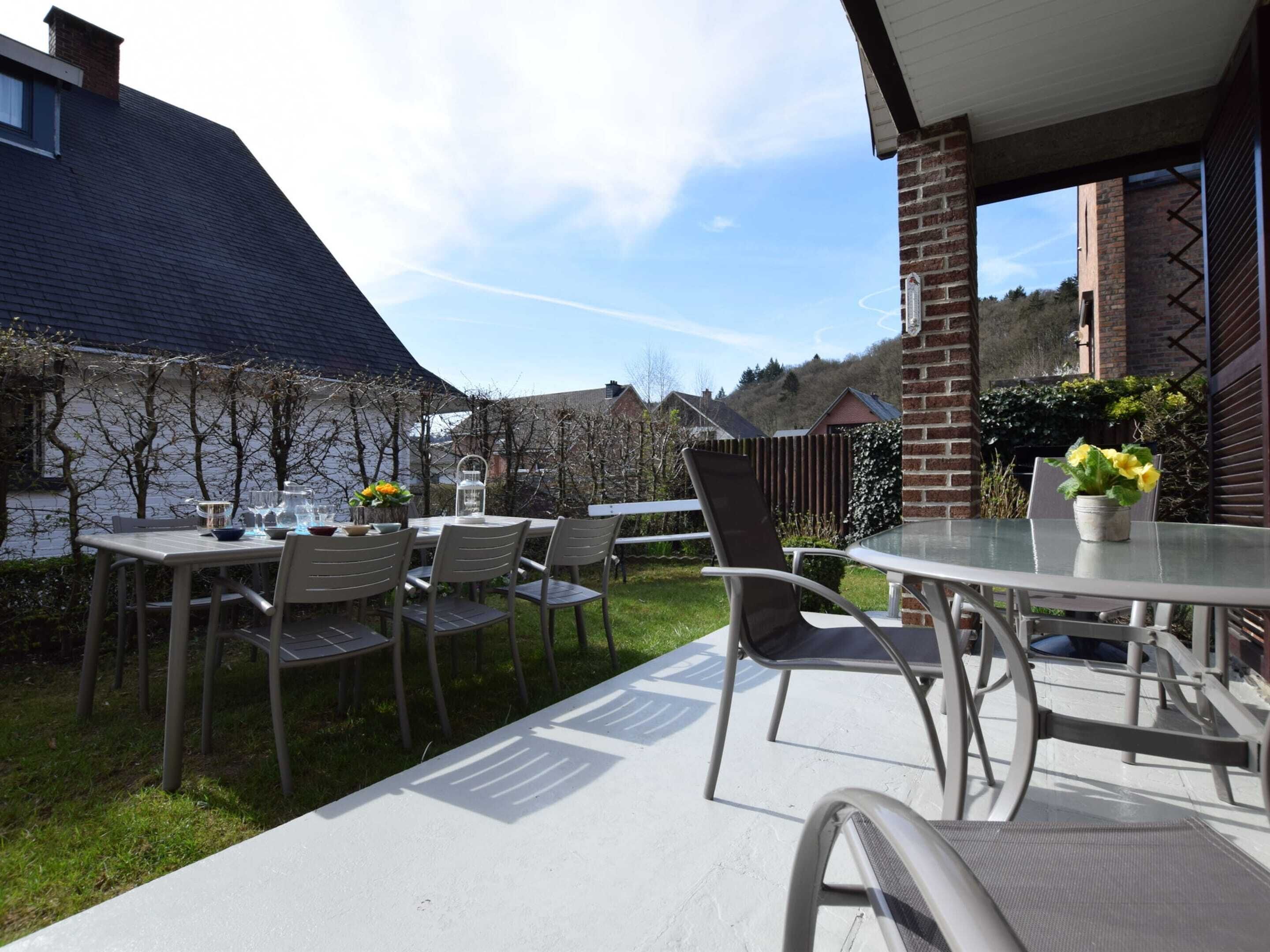 An outdoor patio with a round table and chairs, a brick wall, and a view of a residential area.