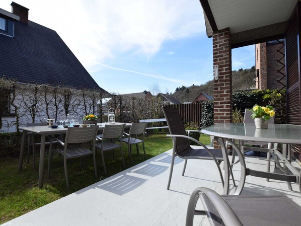 An outdoor patio with a round table and chairs, a brick wall, and a view of a residential area.
