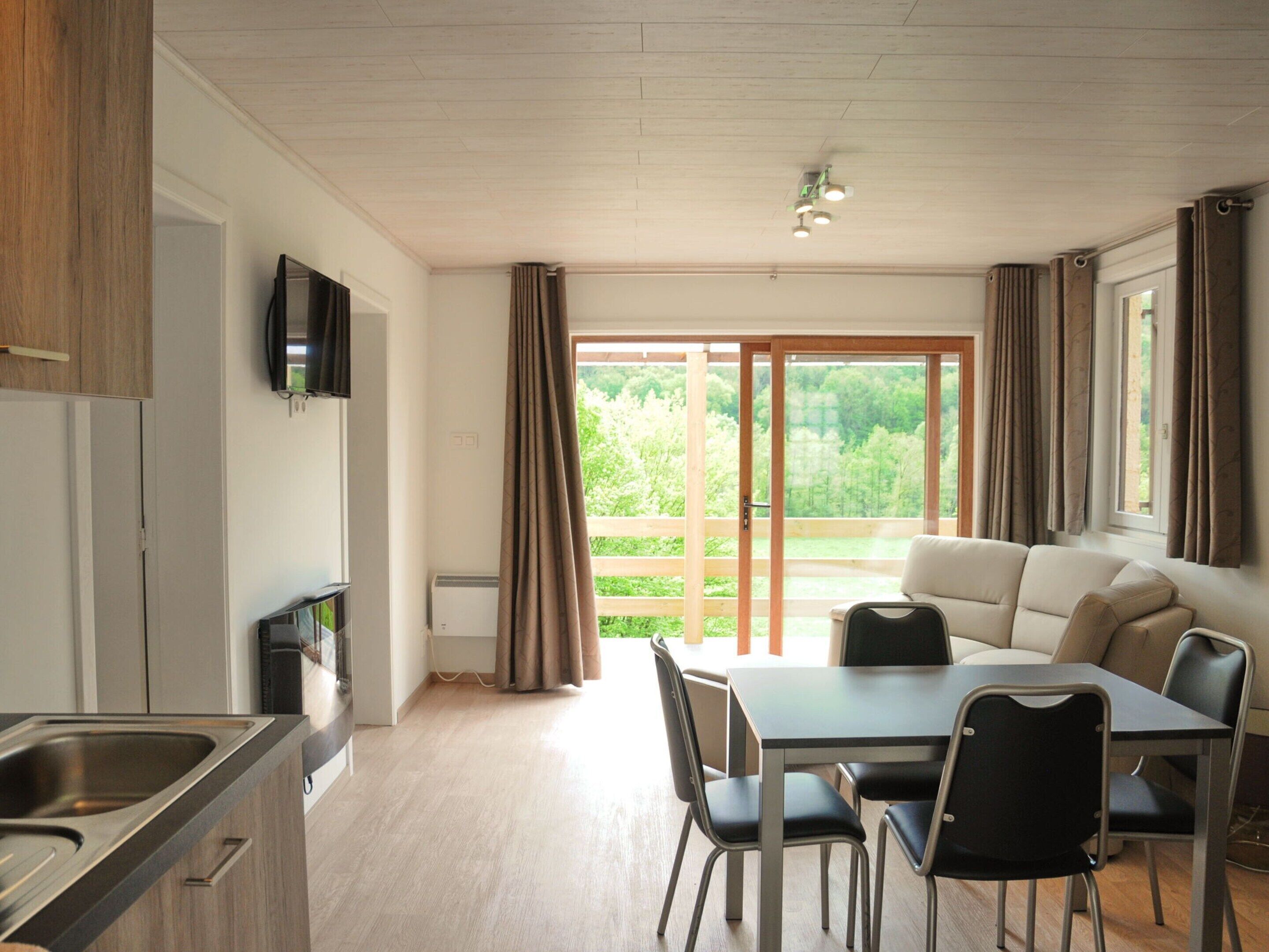 Een moderne keuken met een eethoek, een bank en een aan de muur bevestigde televisie.