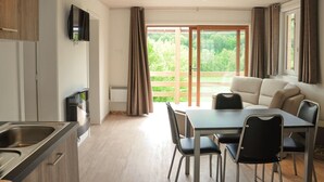 A modern kitchen with a dining area, a sofa, and a TV mounted on the wall. - Holiday Home in Duruby With Garden & BBQ (Durbuy)