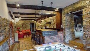 A cozy indoor space with a foosball table, a red sofa, and a stone wall. - Holiday Home in Trois Ponts With Private Pool (Trois-Ponts)
