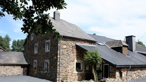 A stone building with a sloped roof, a small porch, and flower boxes. - Holiday Home in Trois Ponts With Private Pool (Trois-Ponts)