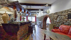 A rustic interior with a brick bar, stone walls, a red leather sofa, and a wooden table. - Holiday Home in Trois Ponts With Private Pool (Trois-Ponts)