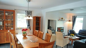 A modern living room with a dining area, wooden furniture, a fireplace, and a television. - Holiday Home in Barvaux With Sauna & Garden (Durbuy)