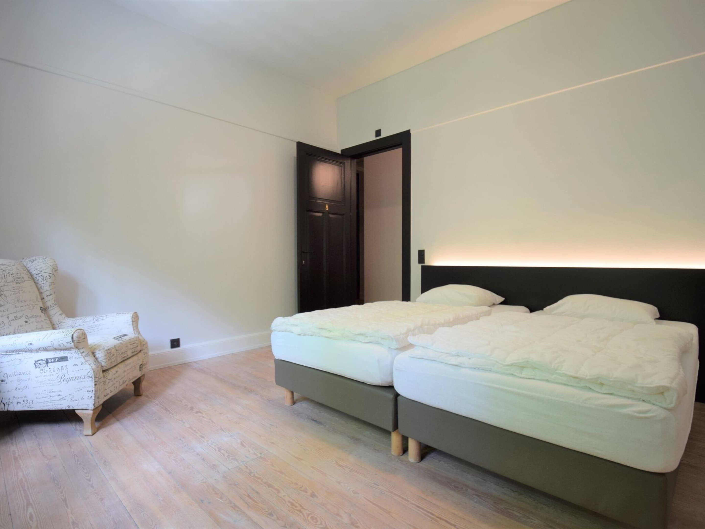 A bedroom with a bed, a chair, and a door.
