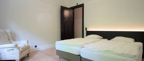 A bedroom with a bed, a chair, and a door.