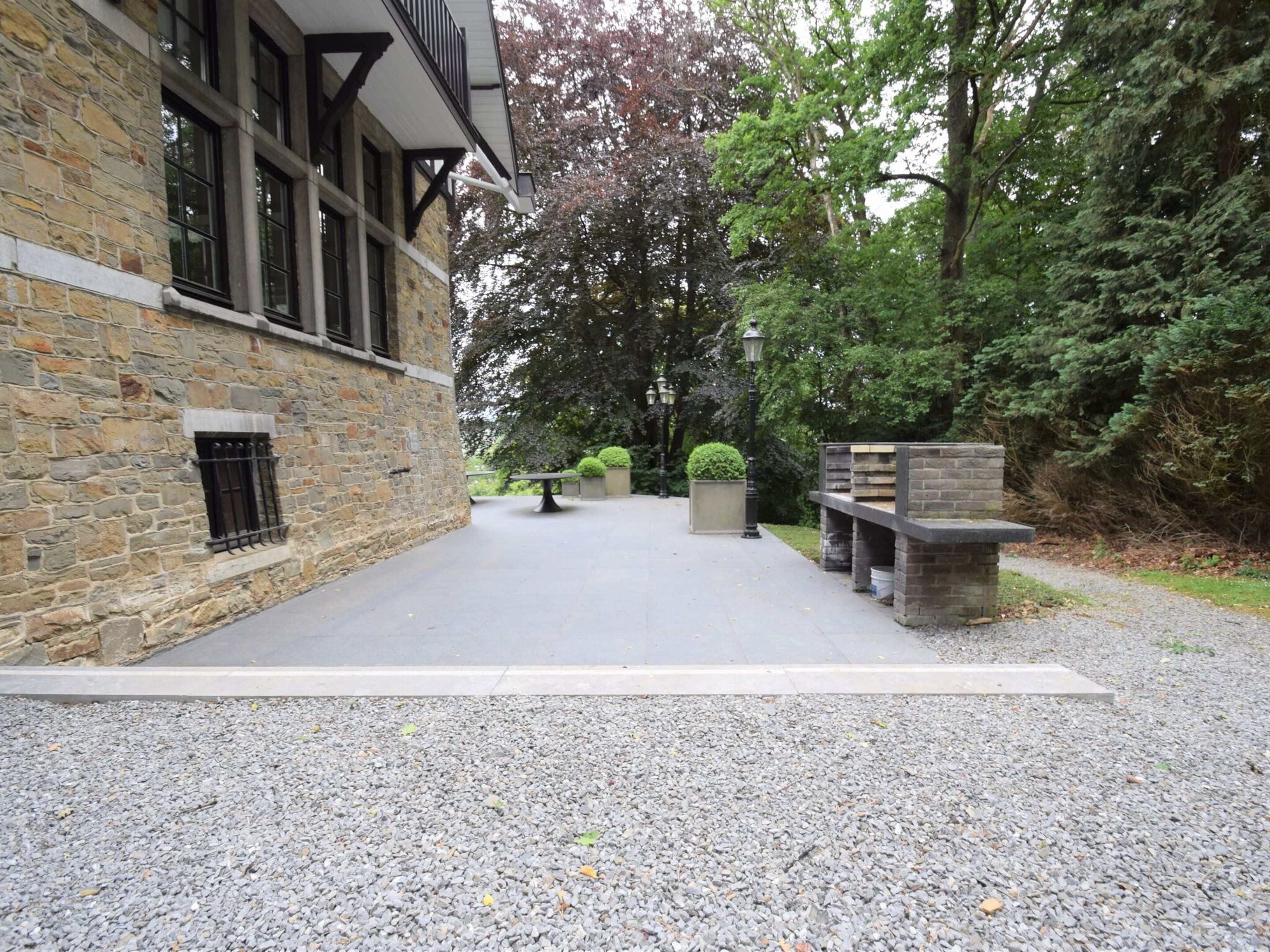 Une cour avec un bâtiment en pierre, un chemin pavé et un banc.
