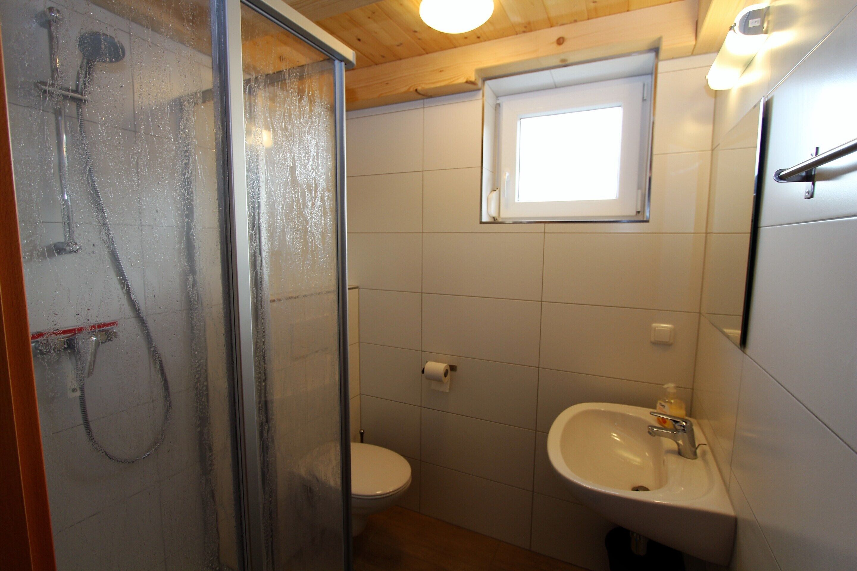 Un baño con cabina de ducha de vidrio, inodoro y lavabo con espejo.