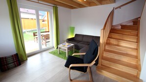 Una sala moderna con una escalera de madera, un sofá, una mesa de centro y una alfombra verde.