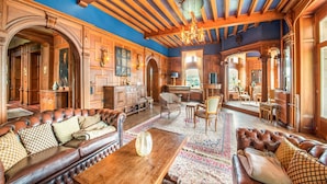 A spacious room with a large wooden sofa, a wooden coffee table, and a dining area with chairs. - Impressive Castle in Spa With a Swimming Pool (Jalhay)