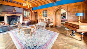 A spacious living room with a fireplace, wooden ceiling beams, and a large rug. - Impressive Castle in Spa With a Swimming Pool (Jalhay)