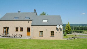 Un bâtiment en briques de deux étages, doté d’un toit en pente, de nombreuses fenêtres et d’antennes paraboliques.