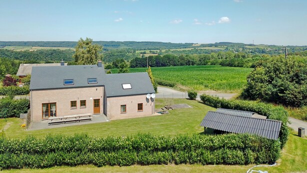 Un grand bâtiment doté de nombreuses fenêtres et d’un toit plat, entouré de champs verdoyants et d’arbres.