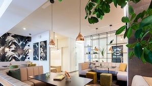A modern interior with a curved seating area, pendant lighting, and a visible plant. - Cottage Famille - Family Resort With Wellness in the Heart of the Ardennes (Malmedy)