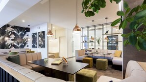 A modern lounge area with a curved seating arrangement, a central table, and pendant lighting. - Cozy Family Cottage for 6 in Ardennes (Malmedy)