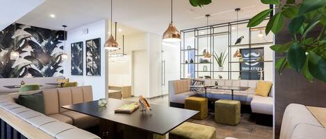 A modern lounge area with a curved seating arrangement, a central table, and pendant lighting.