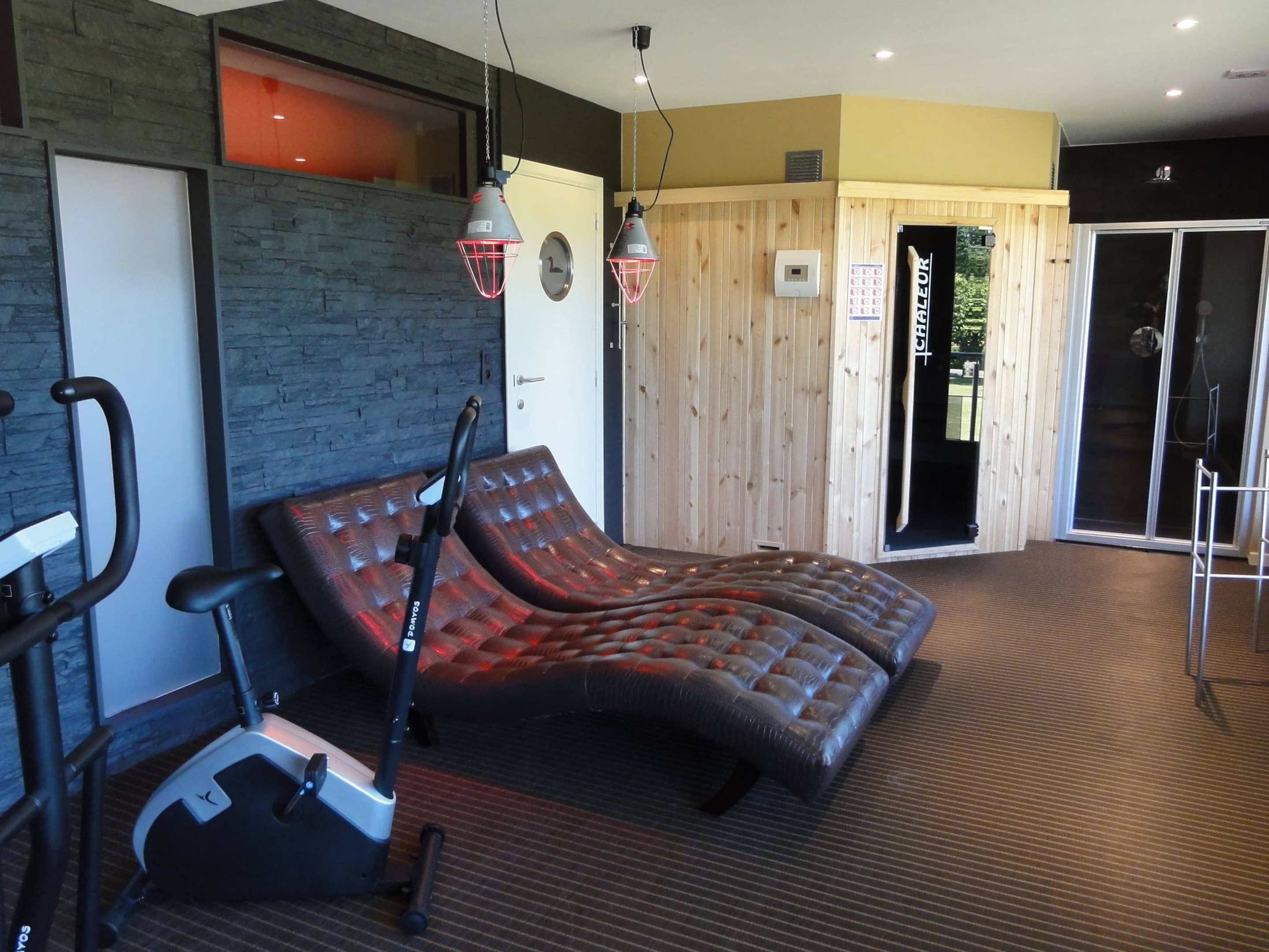 A massage chair, exercise bike, and a wooden wall with a sliding door.