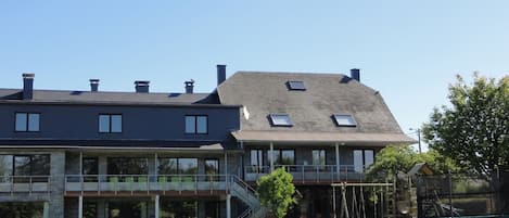A modern building with a flat roof, multiple windows, and a covered outdoor area with a staircase.