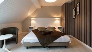 A modern bedroom with a bed, bedside tables, a chair, and a small table. - Swanky Holiday Home in Waimes With Indoor Swimming Pool (Waimes)