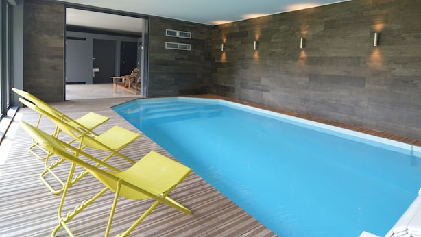 Ein Hallenbad mit Holzboden und gelben Stühlen.