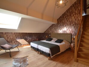 Un dormitorio con una cama grande, una silla, una alfombra y una escalera.