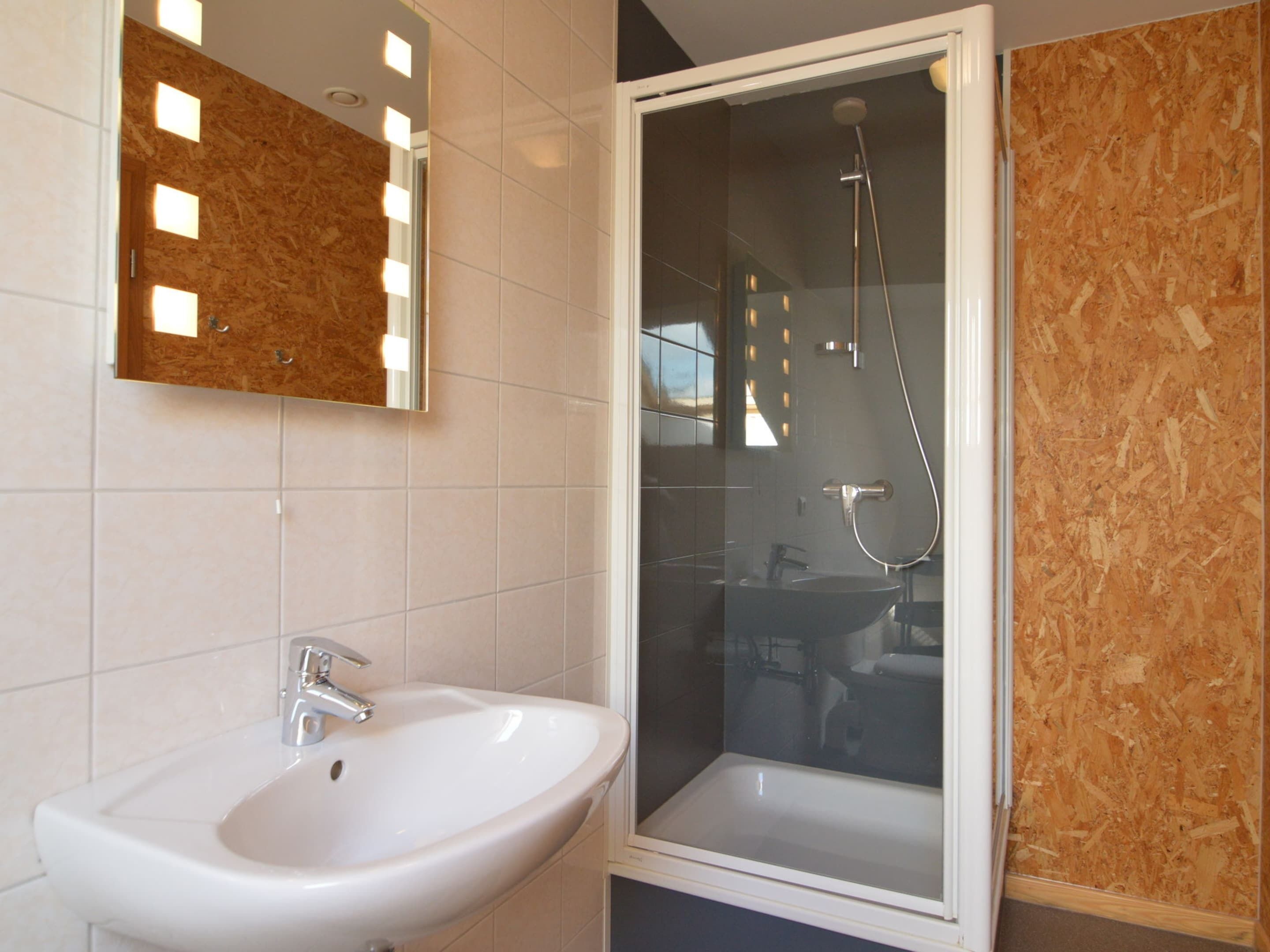 Un baño con lavamanos blanco, espejo y cabina de ducha de vidrio.