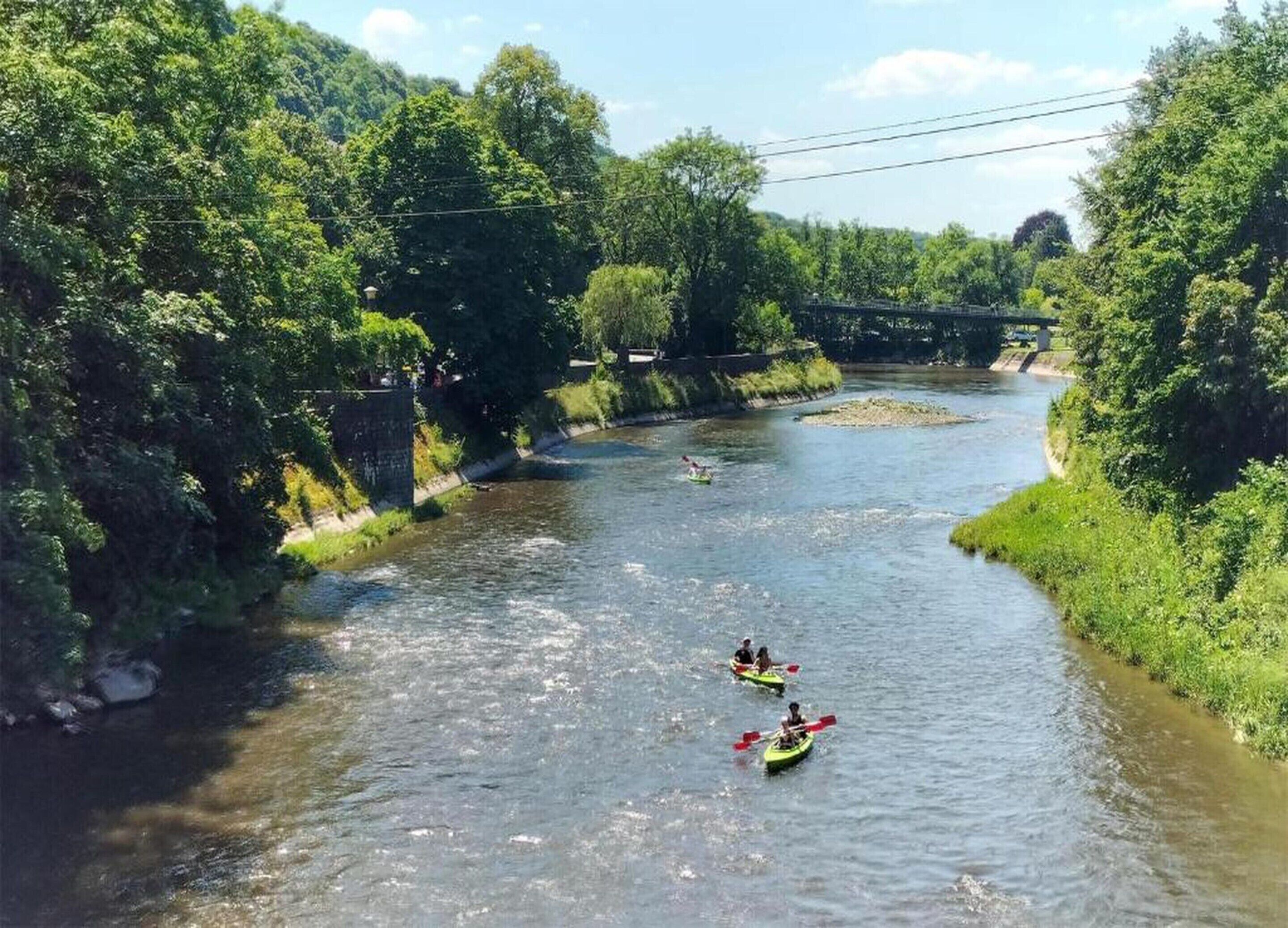 Une rivière où l’on peut faire du kayak, bordée d’une végétation luxuriante, avec un pont en arrière-plan.