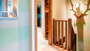 A hallway with striped walls, a wooden staircase, and a deer head mounted on the wall. - Luxurious Holiday Home With Sauna in Fauvillers (Fauvillers)