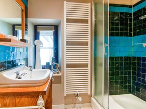 A bathroom with a white sink, wooden vanity, a window with blinds, a white towel rack, and a shower with blue-tiled walls. - Luxurious Holiday Home With Sauna in Fauvillers (Fauvillers)