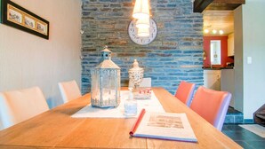 A dining area with a wooden table, chairs, a decorative lantern, and a clock on the wall. - Luxurious Holiday Home With Sauna in Fauvillers (Fauvillers)