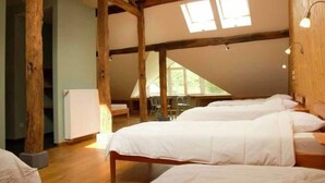Una habitación con dos camas, vigas de madera y tragaluces.