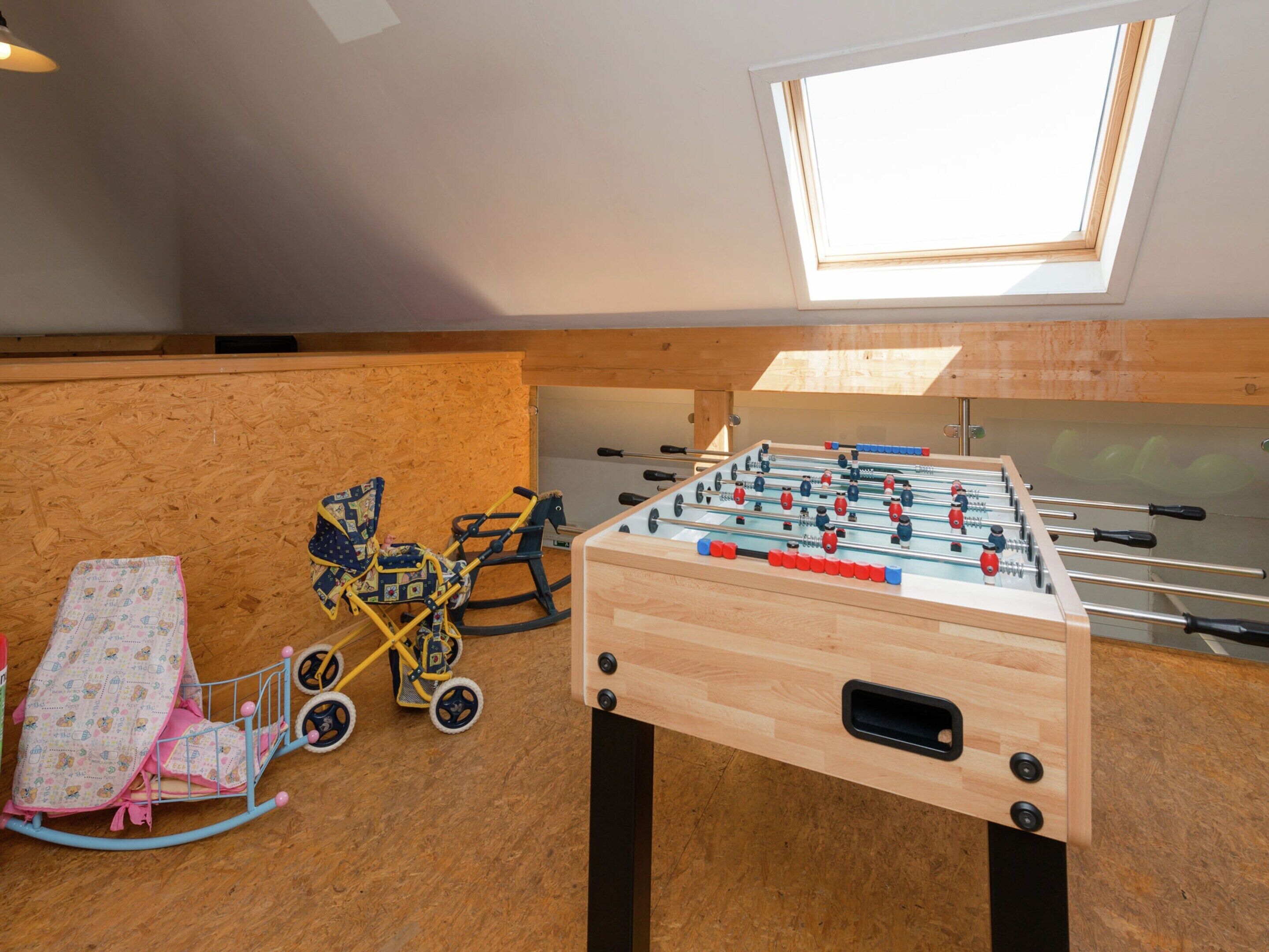 A room with a foosball table, a rocking chair, and a crib.