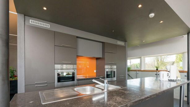A modern kitchen with grey cabinetry, stainless steel appliances, and a granite countertop. - Comfy Home with Sauna Located near Forest (Waimes)