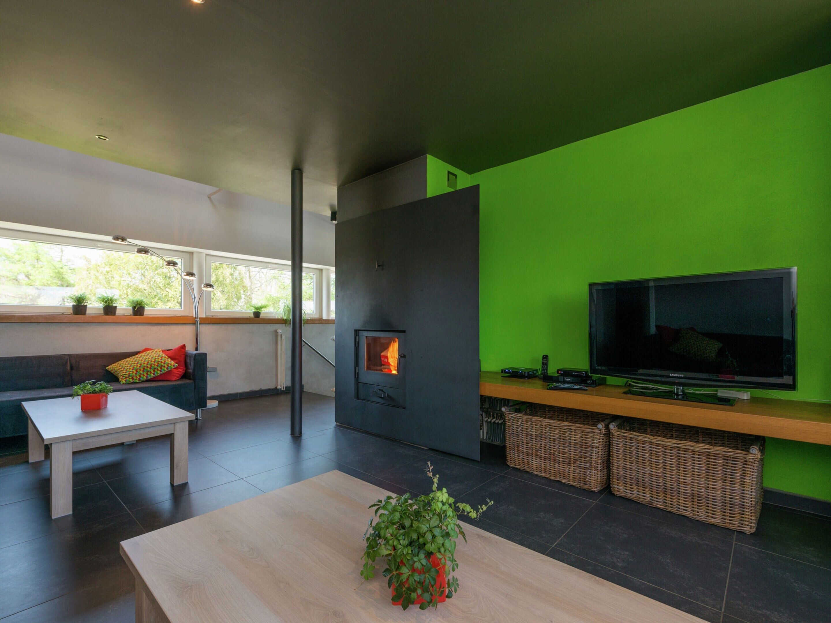 Una sala de estar moderna con chimenea, un televisor de pantalla plana y una pared de acento verde.