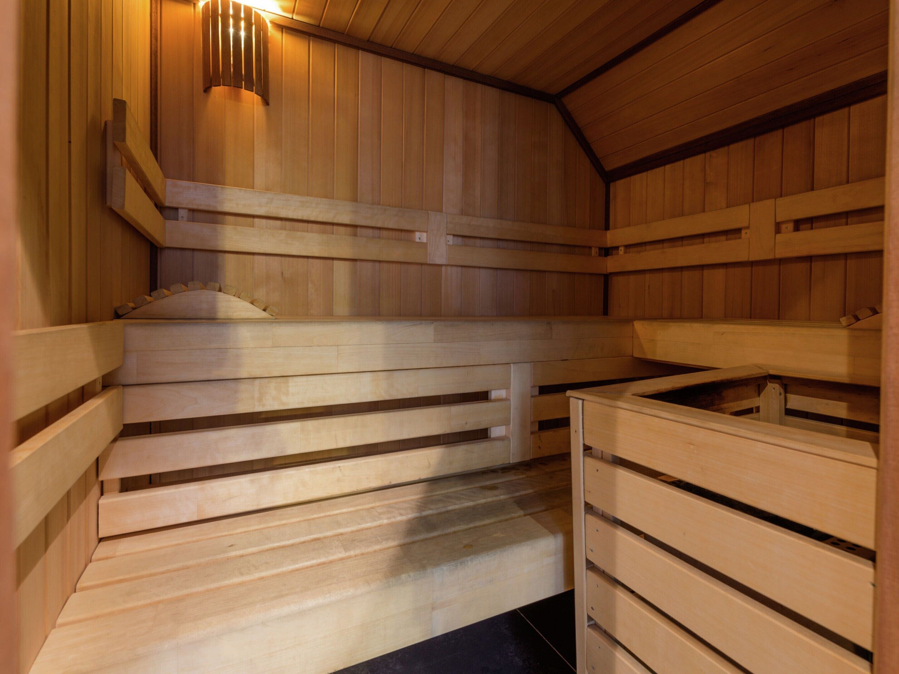 Una sauna in legno con panche e un elemento riscaldante centrale.