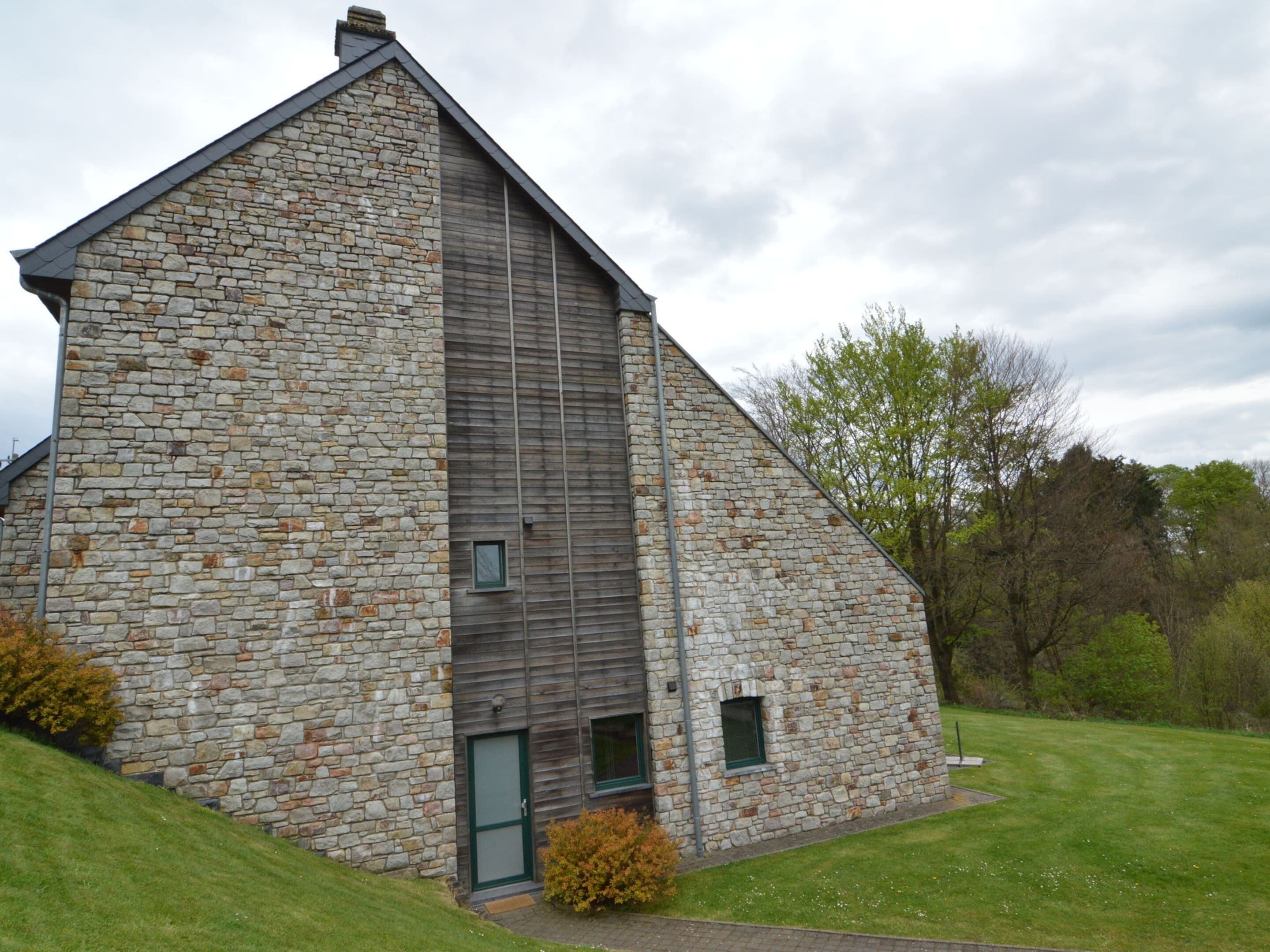 A stone building with a sloped roof, a small door, and a window.