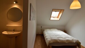 Une chambre à coucher avec un puits de lumière, une table de chevet et un lit.
