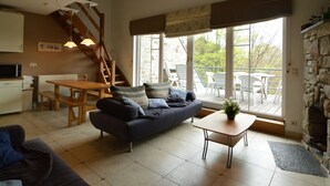 Un vaste espace de vie comprenant un canapé, une table à manger et un escalier.