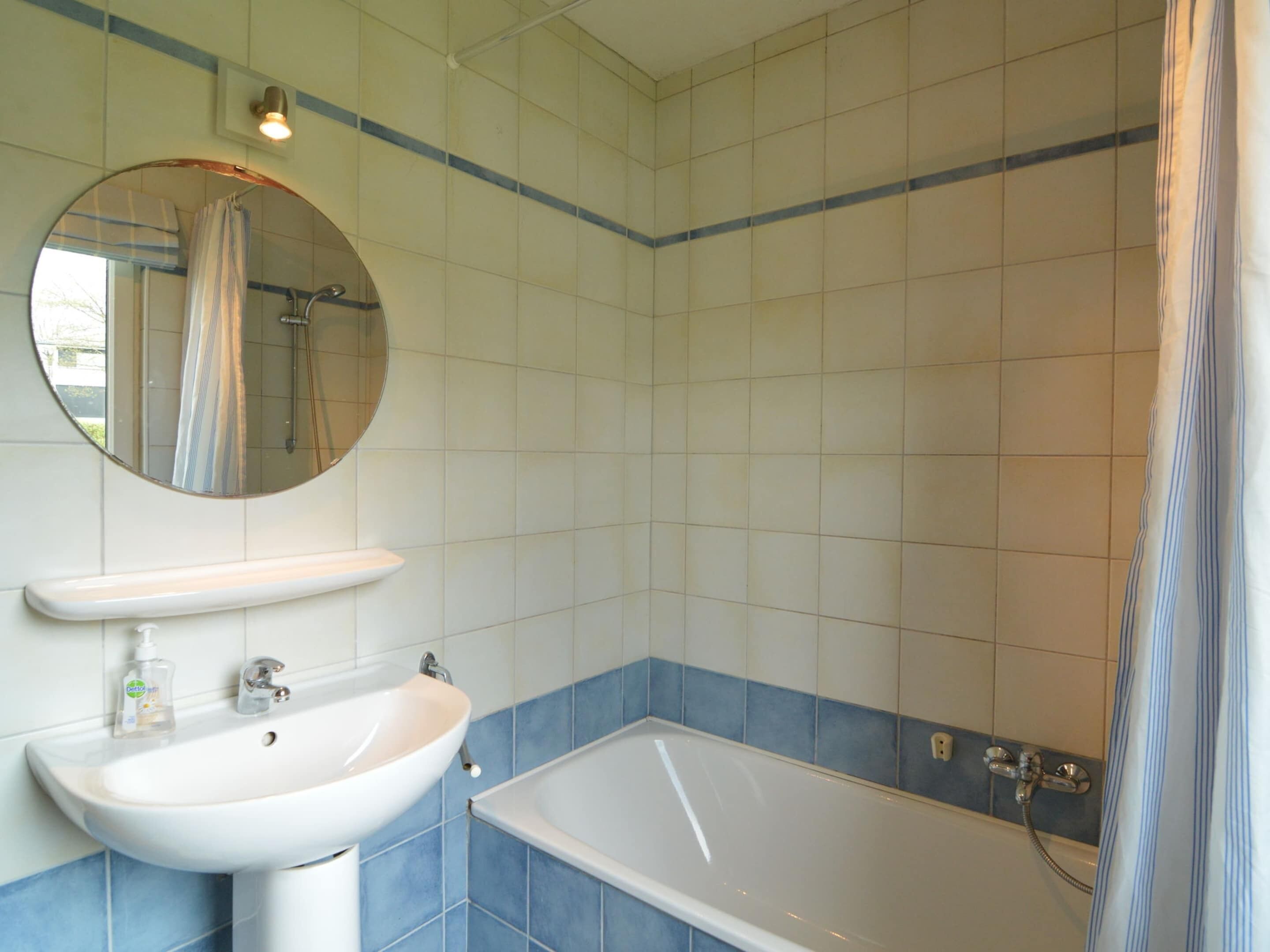 A bathroom with a sink, mirror, and bathtub.