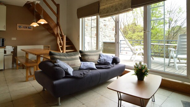 Un salon confortable avec un canapé, une table à manger et un escalier menant à un espace extérieur.
