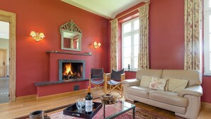 A living room with a fireplace, a sofa, a coffee table, and a red patterned rug.