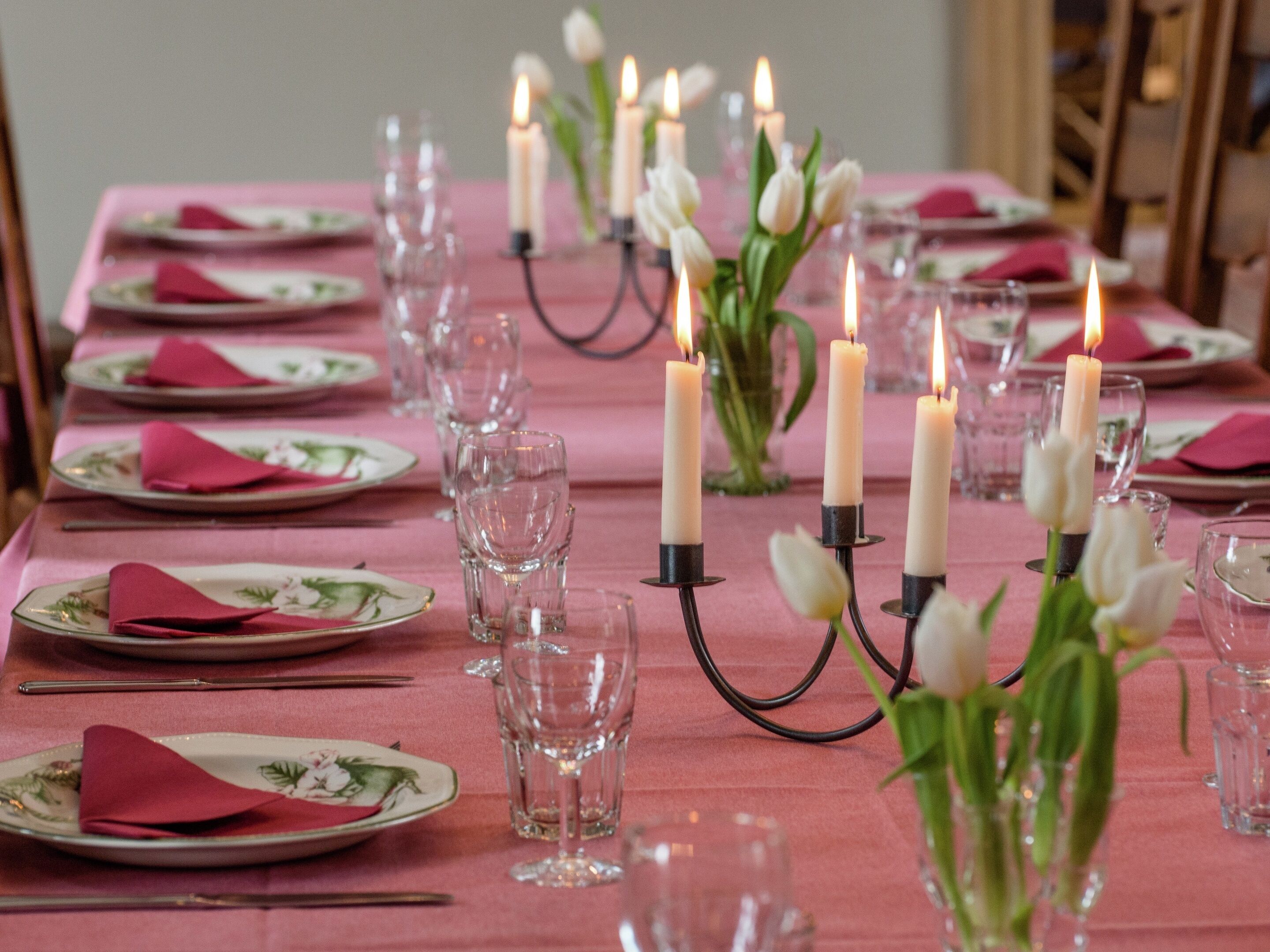 Una mesa dispuesta para comer, con platos, vasos y velas.