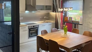 Eine moderne Küche mit weißen Schränken, einem eingebauten Ofen und einem Essbereich mit Holztisch und Stühlen.