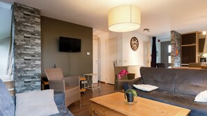 Ein modernes Wohnzimmer mit grauem Sofa, einem Holztisch und einer Wand mit Steinverkleidung.