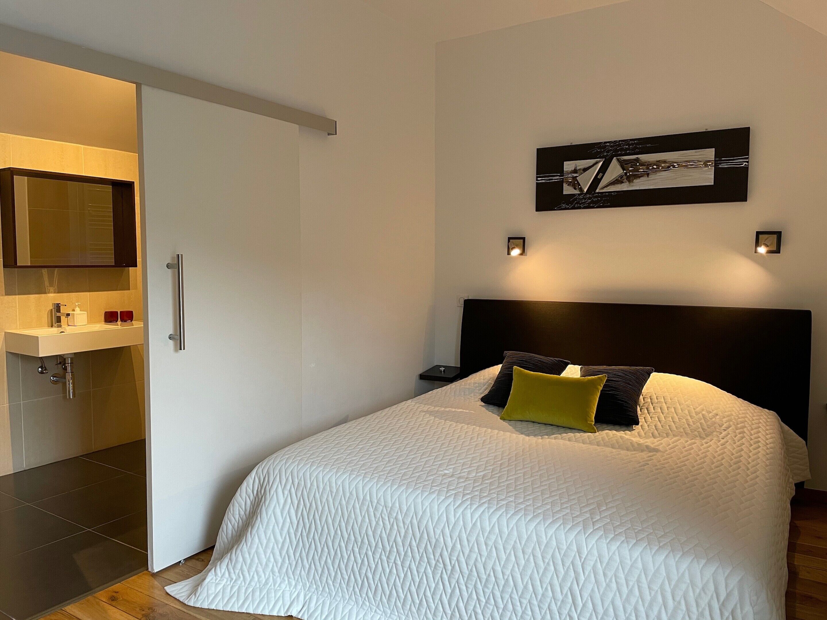 Une chambre à coucher avec un lit, une table de chevet et un tableau accroché au mur.