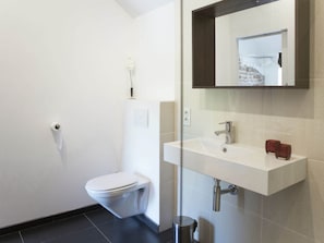 Ein modernes Badezimmer mit Toilette, Waschbecken und Spiegel.