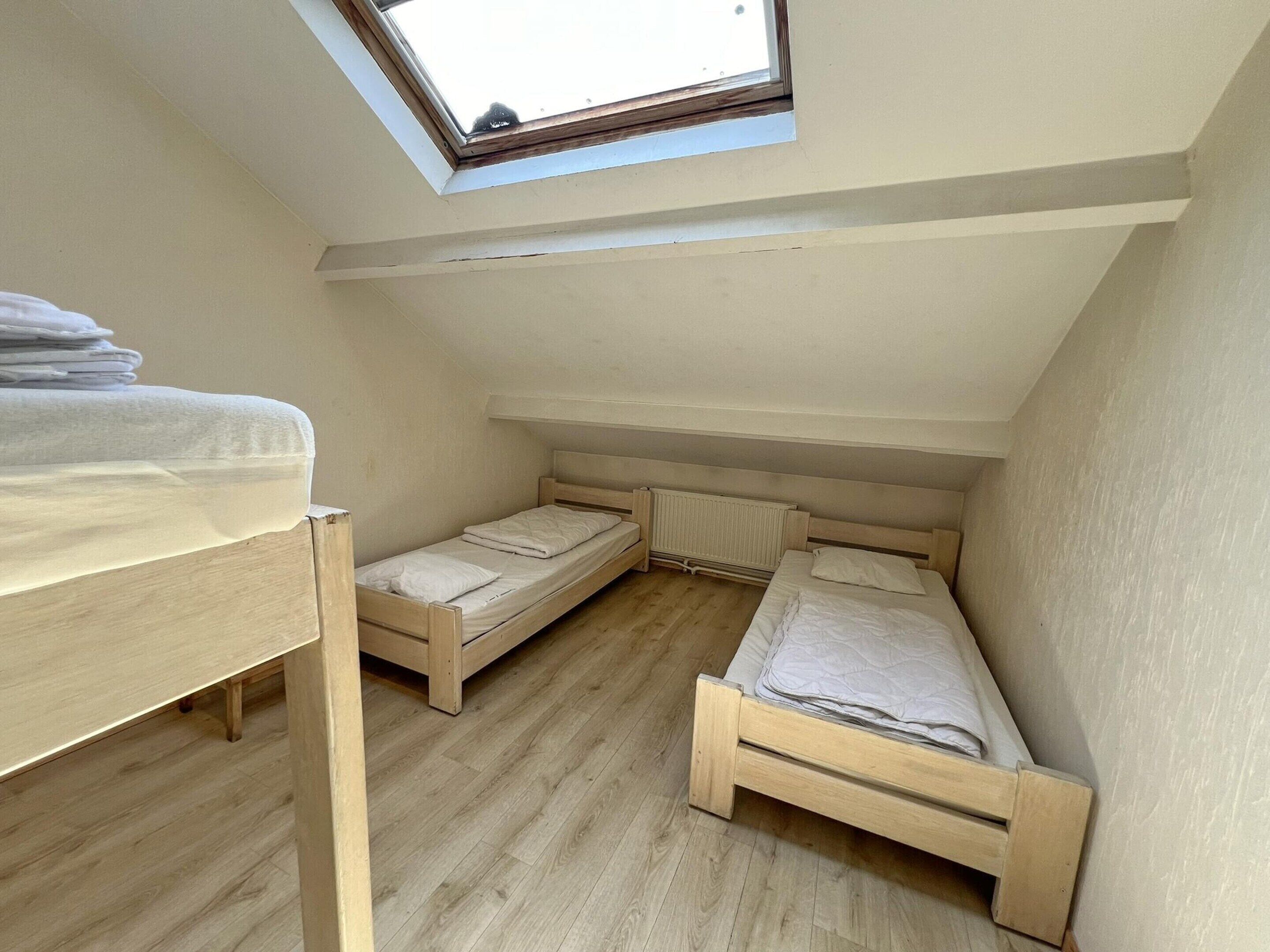 Un apartamento pequeño de una sola habitación con techo inclinado, tragaluz y dos camas de madera.