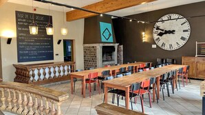 A restaurant with a long wooden table, chairs, a blackboard menu, a large wall clock, and a stone fireplace. - House near Caves of Hotton, L' Ourthe, & Durbuy (Somme-Leuze)